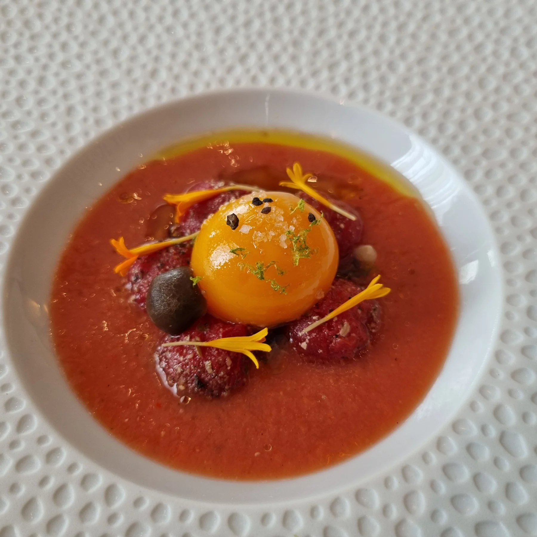 Jaune d'oeuf et tomates cerises confits à l'huile d'ail, sauce sésame, gaspachio et champignons Shimeji.