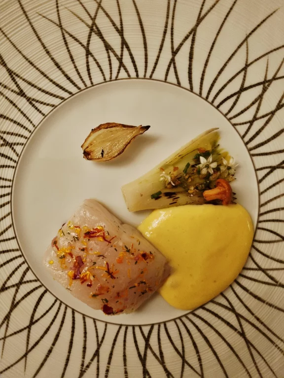 Sandre confit au beurre avec un poireau et un oignon servis avec une sauce au vin blanc de Suresnes.