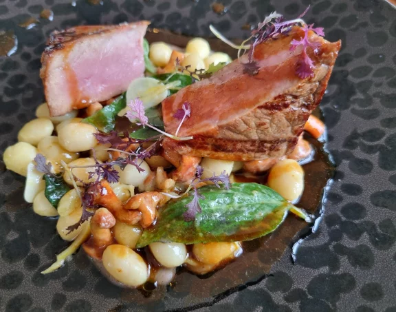 Longe de lait de veau fumée servie avec des cocos de Paimpol, des girolles, des pousses d'épinards et une purée d'ail noir.