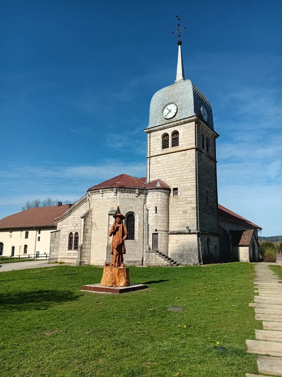 L'église de Grande-Rivière sur le site de l'ancienne abbaye. En premier plan, la statue du roulier de Grandvaux