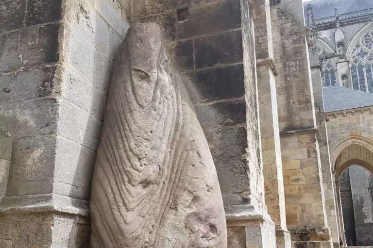 Ce menhir sculpté en grès rose date de l'époque préhistorique. Il ressemble à une femme portant un drapé.