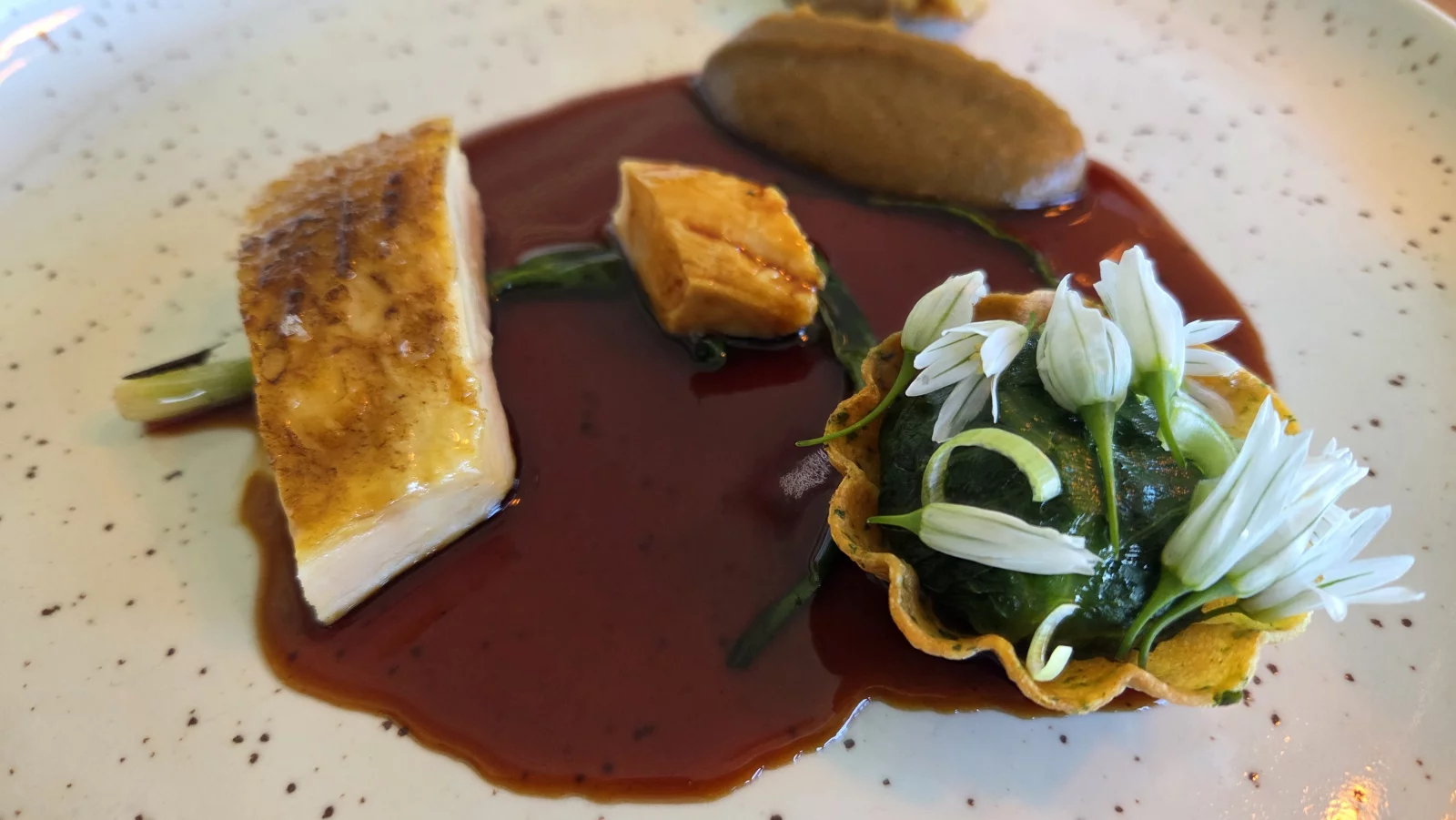 La volaille dans tous ses états : rôtie, pochée, confite accompagnée d'une tartelette mêlant le foie, les gésiers et l'aile du volatile avec de l'épinard et des fleurs d'ail. Au second plan, une purée échalotte-oignon.