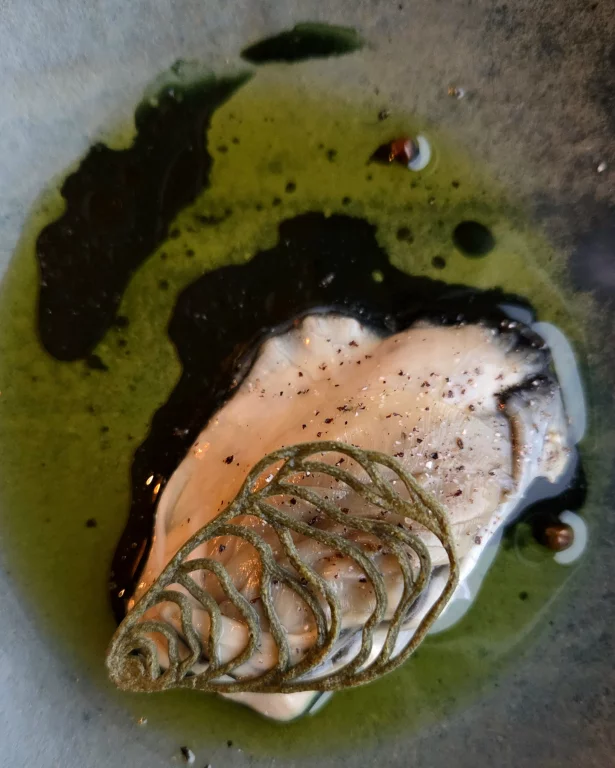 Ormeau travaillé avec de l'échalotte noircie, sauce à la feuille de moutarde.