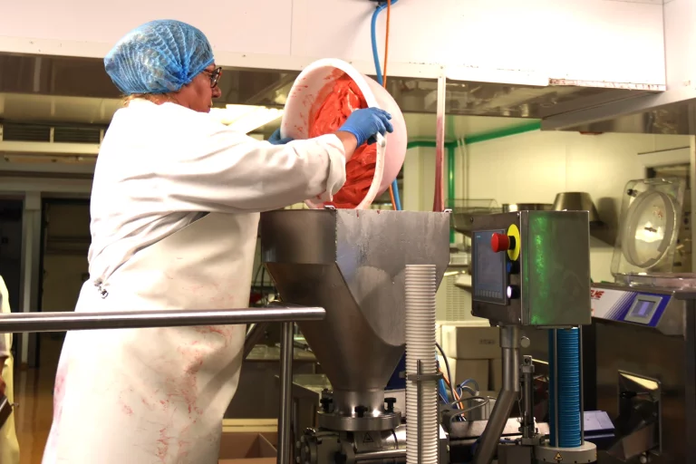 Ce jour-là, Annie était responsable de la fabrication de la glace à la fraise. Elle verse la matière glacée dans l'entonnoir qui remplit les petits pots.