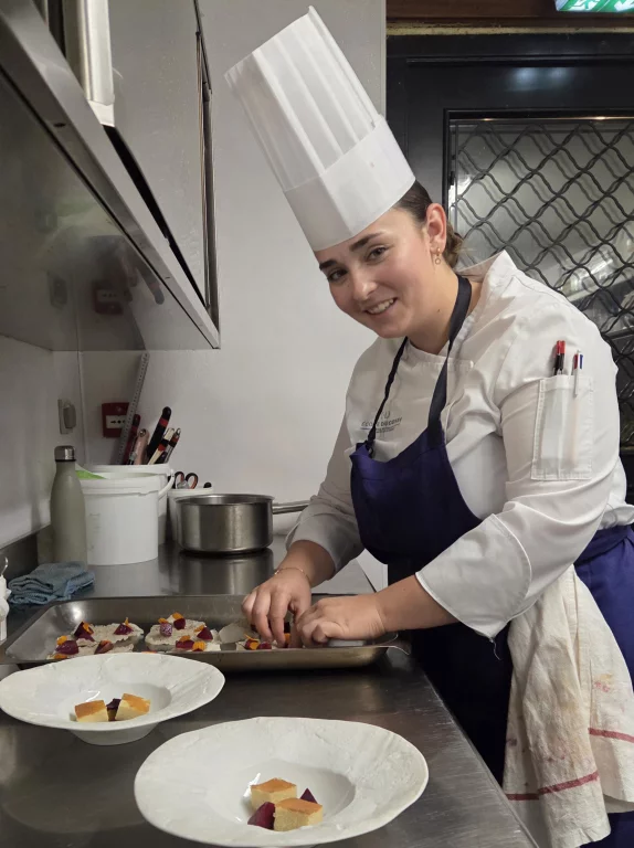 La chef pâtissière préparant un dessert avec de la prune confite, en sorbet, accompagné d'un biscuit au pain de Gênes et d'une émulsion crémeuse à la vanille de Madagascar.