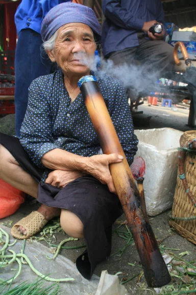 Cette dame fume une longue pipe à eau en bambou.